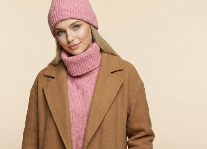 Frau mit langen blonden Haaren, Rollkragenpullover, Wintermantel und M&uuml;tze