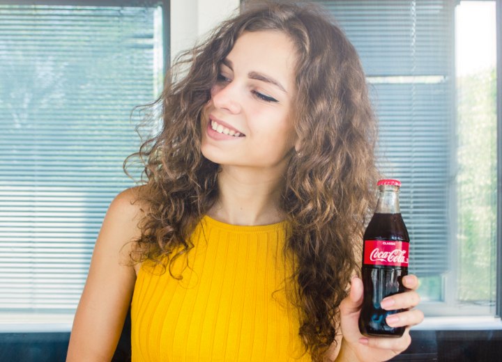 Frau mit langen lockigen Haaren und Coca Cola